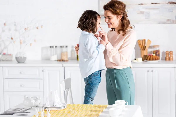 Mère et enfant souriants dans la cuisine près de la table avec nappe jaune — Photo de stock