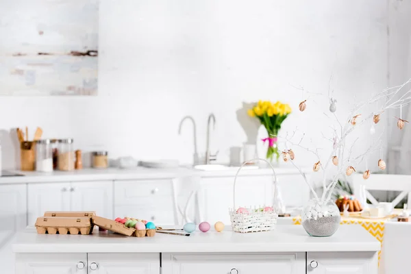 Arbre de Pâques, œufs peints et panier de guichet sur la table dans la cuisine — Photo de stock