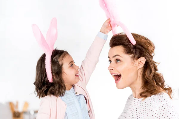 Mother and daughter in bunny ears having fun on white — Stock Photo