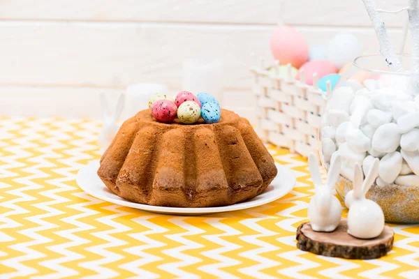 Easter bread with colorful painted eggs and ceramic rabbits on table — Stock Photo