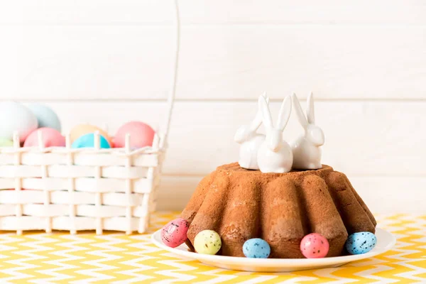Pastel de Pascua con conejitos de cerámica y huevos de codorniz pintados en la mesa - foto de stock