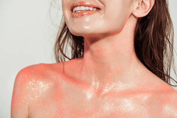 Vue recadrée d'une femme nue souriante recouverte de paillettes de corail isolée sur gris — Photo de stock