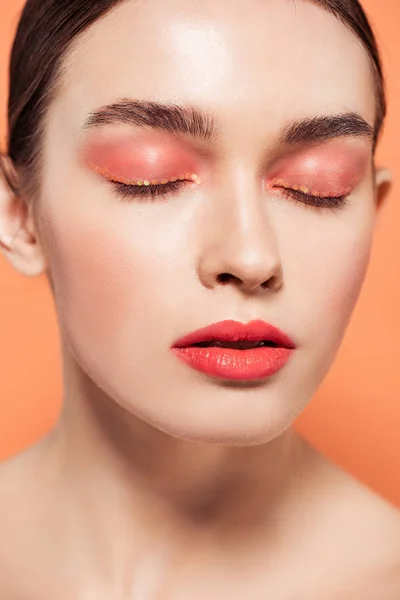 Beautiful trendy young woman with glitter makeup and eyes closed isolated on coral — Stock Photo