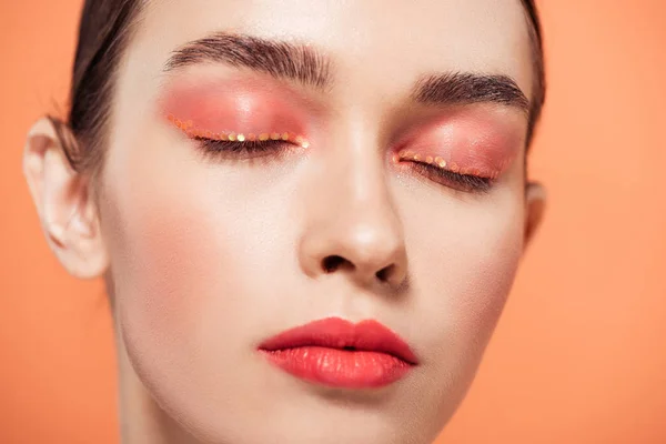 Bela jovem da moda com maquiagem brilho e olhos fechados isolados em coral — Fotografia de Stock