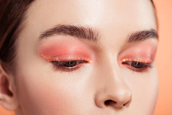 Primer plano de mujer hermosa con maquillaje posando aislado en coral - foto de stock