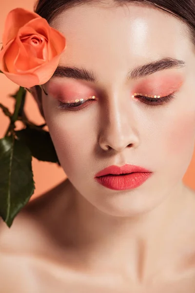 Belle fille élégante avec fleur rose posant isolé sur le corail — Photo de stock