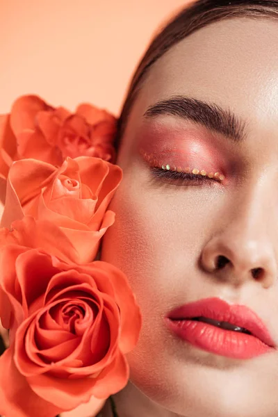 Atractiva chica elegante posando con flores de rosas aisladas en coral - foto de stock