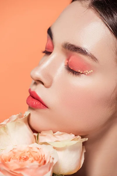 Hermosa chica elegante posando con flores de rosas aisladas en coral - foto de stock