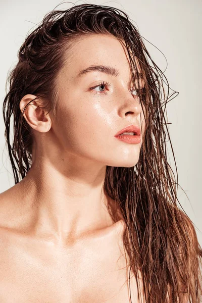 Beautiful young woman with coral lips and wet hair looking away isolated on grey — Stock Photo