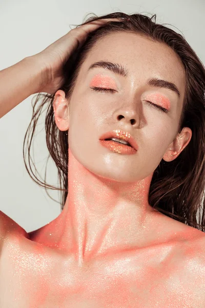 Hermosa chica desnuda con maquillaje de brillo de coral posando aislado en gris - foto de stock