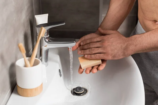 Visão cortada do homem segurando sabão enquanto lavava as mãos no banheiro — Fotografia de Stock