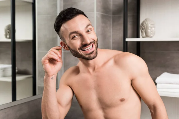 Alegre hombre sin camisa oreja de limpieza en el baño - foto de stock