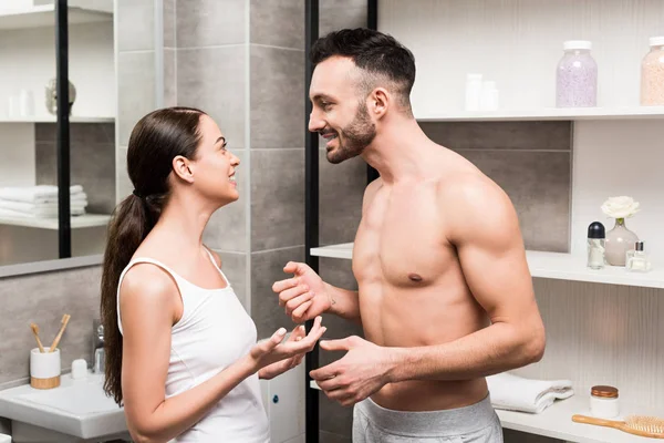 Fröhliches Paar schaut einander beim Gespräch im Badezimmer an — Stockfoto