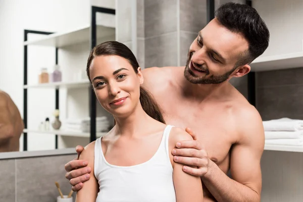 Alegre barbudo hombre mirando atractiva mujer en cuarto de baño - foto de stock