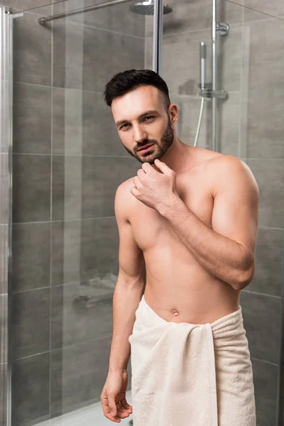 Стомлений м'язистий чоловік стоїть у сучасній ванній кімнаті — стокове фото