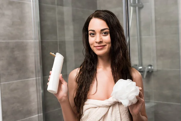 Mulher morena alegre segurando gel de chuveiro e loofah nas mãos — Fotografia de Stock