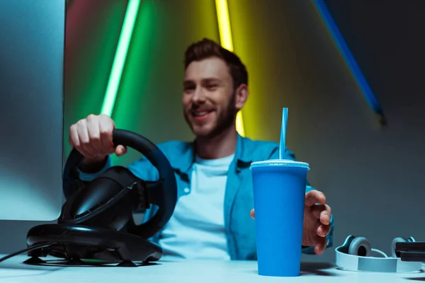 Selective focus of paper cup with soda holding by man playing video game — Stock Photo