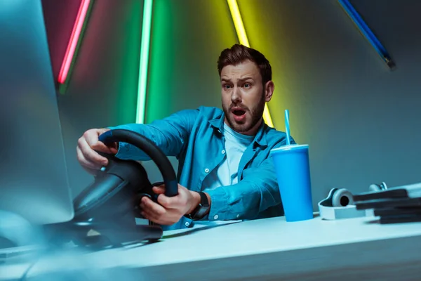 Bonito e bonito homem jogando videogame com volante — Fotografia de Stock