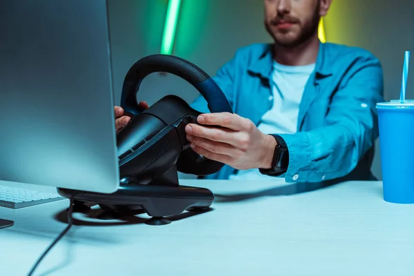 Selective focus of cyber sportsman playing video game with steering wheel — Stock Photo