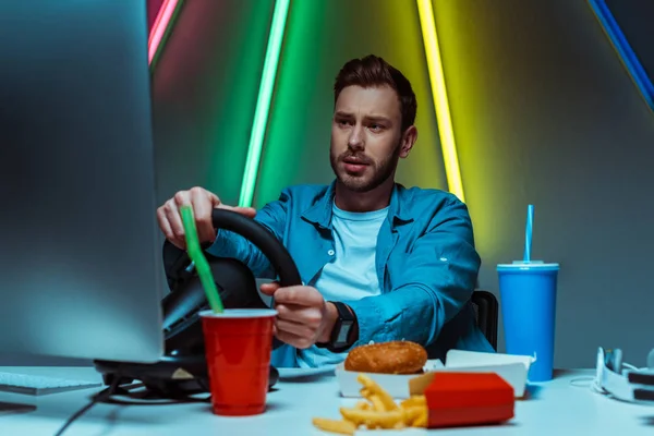 Selective focus of handsome man playing video game with steering wheel — Stock Photo