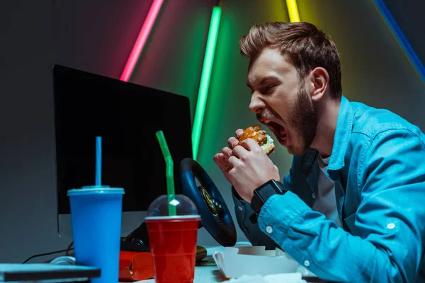 Foyer sélectif de bel homme beau et beau manger hamburger savoureux — Photo de stock