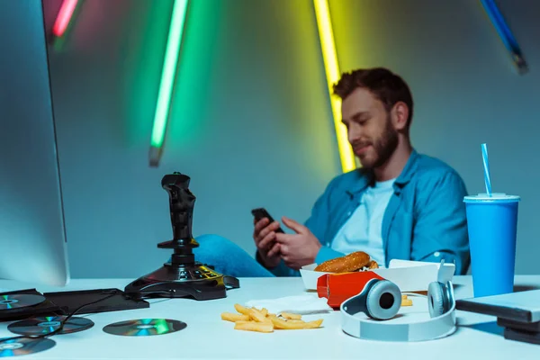 Enfoque selectivo del hombre guapo y guapo usando el teléfono inteligente - foto de stock