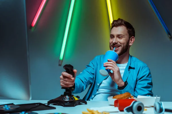 Hombre guapo sosteniendo joystick y beber soda de la taza de papel - foto de stock