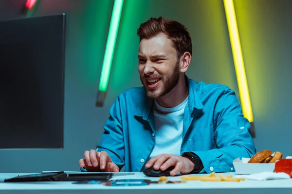 Hombre guapo y feliz jugando videojuego con el ratón de la computadora y el teclado - foto de stock