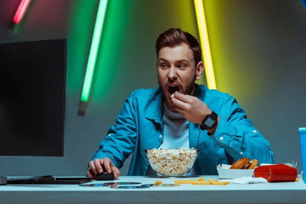 Guapo y guapo hombre sosteniendo el ratón de la computadora y comer palomitas de maíz - foto de stock