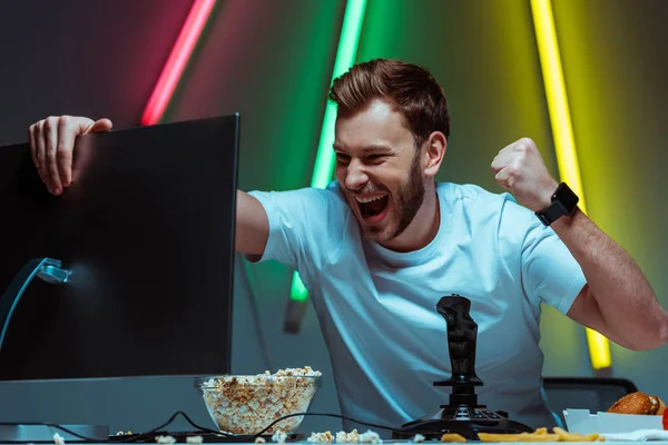 Bonito e feliz homem segurando monitor de computador e mostrando sim gesto — Fotografia de Stock