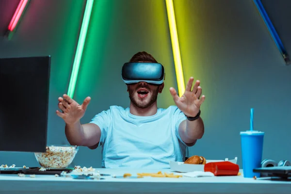 Uomo bello e sorpreso utilizzando auricolare realtà virtuale in appartamento — Foto stock