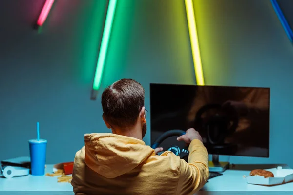 Back view of man playing video game with steering wheel — Stock Photo