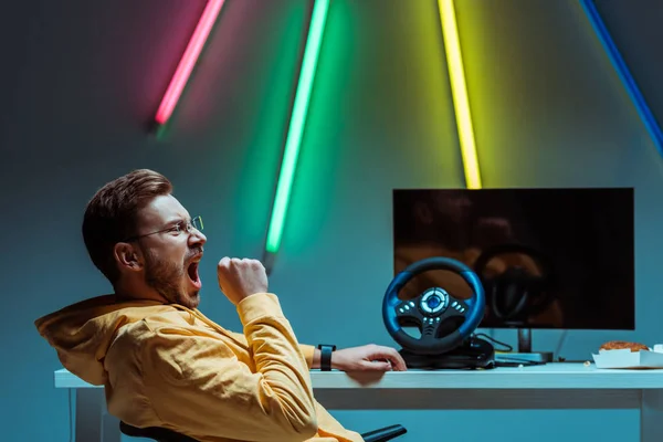 Side view of good-looking and handsome man in glasses sitting and yawning — Stock Photo