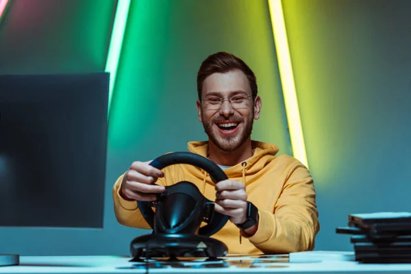 Sorridente, bonito e bonito homem de óculos jogando videogame com volante — Fotografia de Stock