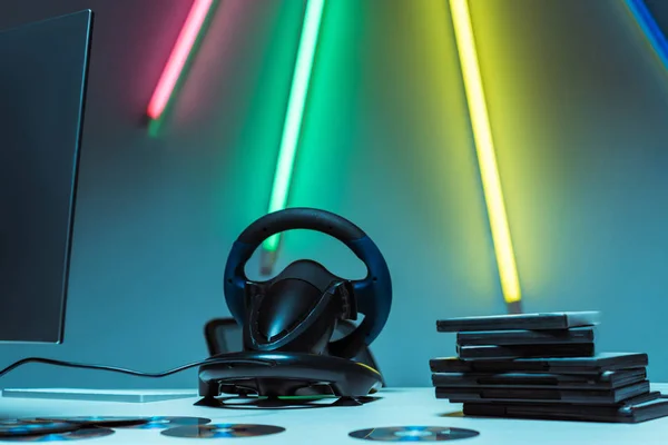 Selective focus of steering wheel and compact disks with video games on table — Stock Photo