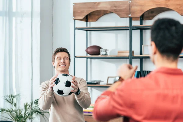 Двоє усміхнених друзів грають з футбольним м'ячем вдома — стокове фото