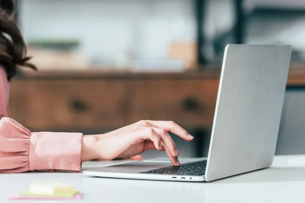 Vista recortada de chica en camisa rosa escribiendo en el teclado del ordenador portátil - foto de stock