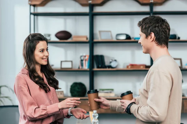 Sorridente giovane uomo dando tazza di carta di caffè alla ragazza — Stock Photo