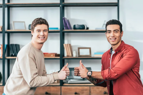 Two smiling multiethnic  friends showing thumbs up and looking at camera — Stock Photo