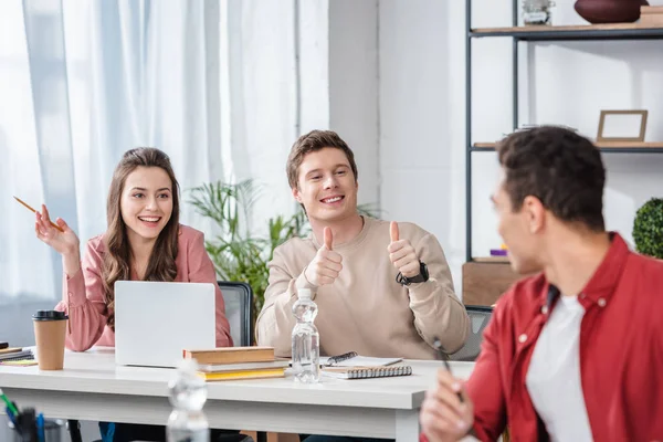 Lächelnde multiethnische Studenten, die einander anschauen und Daumen nach oben zeigen — Stockfoto