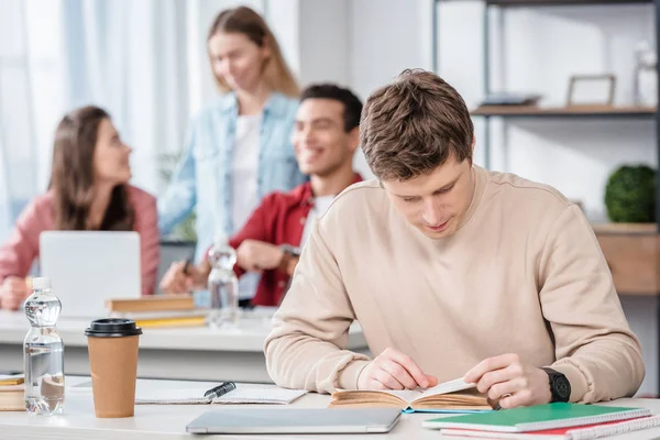 Concentrated student sitting at desk and reading book in classroom — Stock Photo