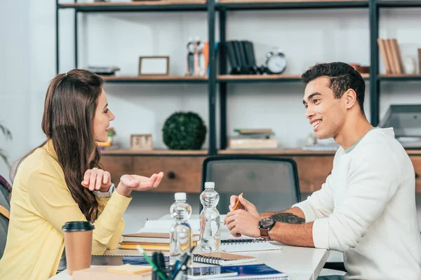 Two multiethnic students sitting at desk with books and studying together — Stock Photo