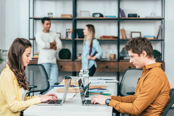 Due studenti seduti a tavola e che lavorano con i computer portatili — Foto stock