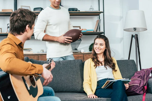 Vue recadrée du jeune homme avec ballon de rugby passer du temps avec des amis à la maison — Photo de stock