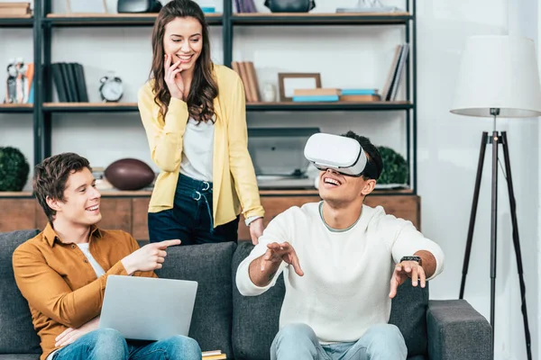 Três amigos rindo usando vr fone de ouvido na sala de estar — Fotografia de Stock