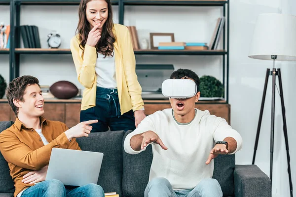 Três amigos rindo usando vr fone de ouvido na sala de estar — Fotografia de Stock