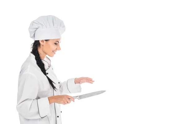 Vista laterale dello chef sorridente in uniforme con coltello isolato su bianco — Foto stock