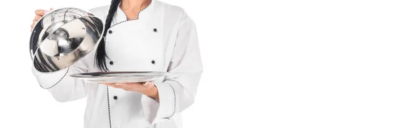 Panoramic shot of chef in uniform holding tray with cloche isolated on white — Stock Photo