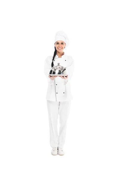 Full length of chef in hat holding tray with cloche isolated on white — Stock Photo