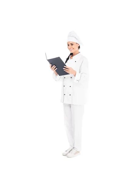 Visão completa do chef sorridente em livro de leitura uniforme isolado em branco — Fotografia de Stock